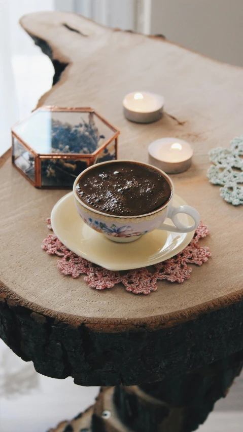 a cup of coffee sitting on top of a wooden table, an album cover, inspired by Elsa Bleda, pexels, hurufiyya, ottoman miniature style, covered with tar, ayahuasca ceremony, gif