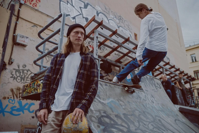 a man riding a skateboard up the side of a ramp, a picture, unsplash, graffiti, two models in the frame, wearing a flannel shirt, federation clothing, caspar david