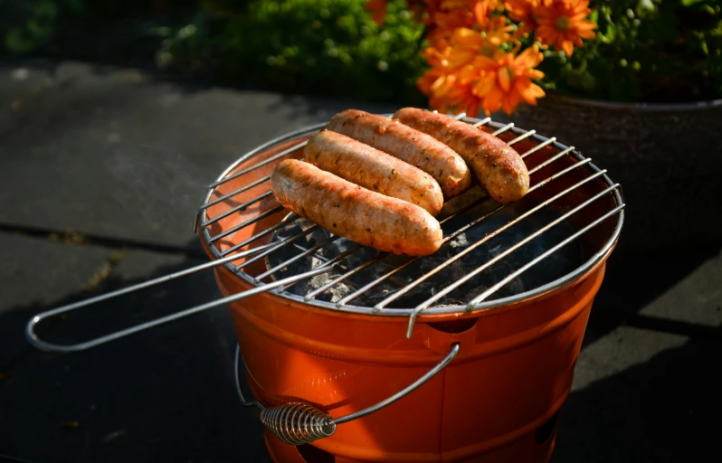 a couple of hot dogs sitting on top of a grill, orange metal ears, 2 1 0 mm, orange, pot