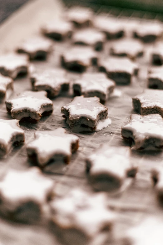 a bunch of cookies sitting on top of a table, a tilt shift photo, by Daniel Gelon, pexels, arabesque, multiple stars visible, covered in white flour, chocolate frosting, thumbnail