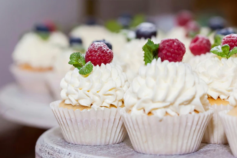 a white plate topped with cupcakes covered in frosting, by Sylvia Wishart, unsplash, berries, festivals, close-up photo, thumbnail