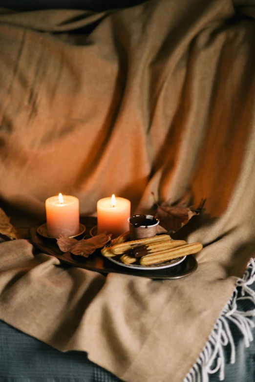 a couple of candles sitting on top of a table, a still life, inspired by Elsa Bleda, trending on pexels, leaves and simple cloth, snacks, brown robes, autum