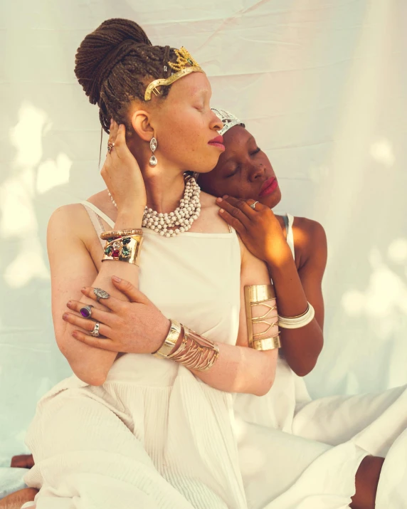 a couple of women sitting on top of a bed, trending on unsplash, afrofuturism, goddess jewelry, holding each other, with a white complexion, singularity sculpted �ー etsy