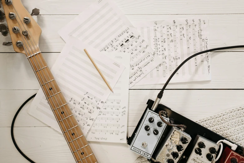 a guitar sitting on top of a wooden table, an album cover, unsplash, pen and paper, background image, various artists, made of notation