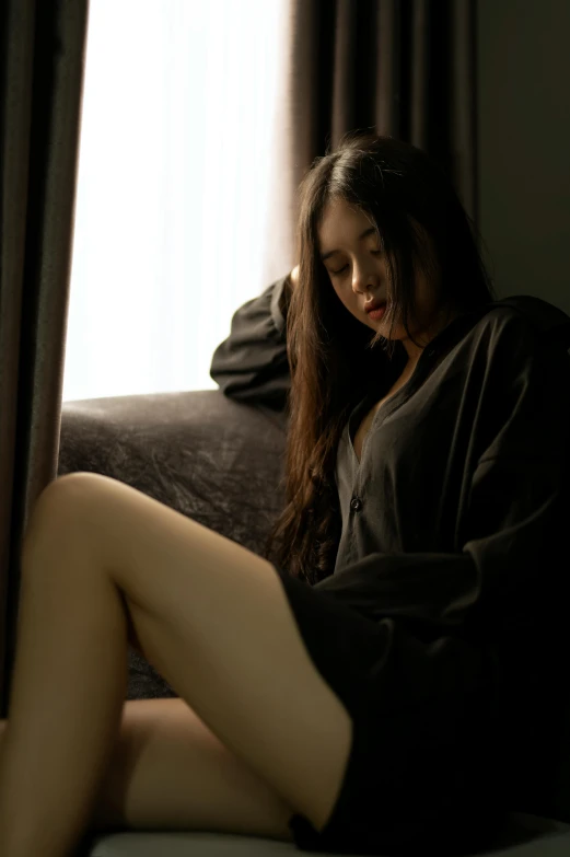 a woman sitting on top of a bed next to a window, inspired by Elsa Bleda, reddit, realism, black haired girl wearing hoodie, wearing black silk robes, thighs close up, gif