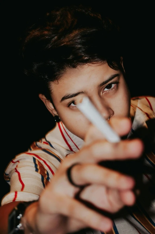 a close up of a person holding a nintendo wii controller, an album cover, by Billie Waters, trending on pexels, dramatic smoking pose, declan mckenna, portrait androgynous girl, cigars