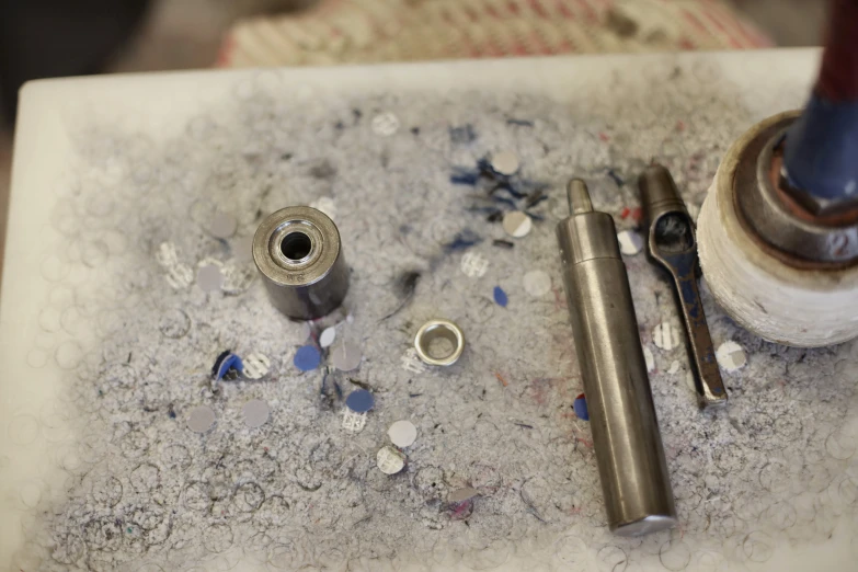 a couple of tools sitting on top of a table, an etching, bullets inside, made of liquid metal and marble, bead and reel, middle shot
