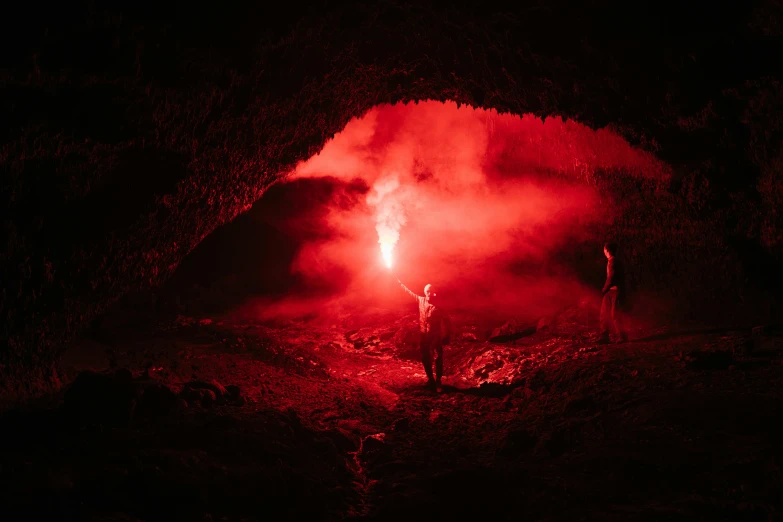 a man that is standing in front of a fire, a cave painting, by Kristian Zahrtmann, pexels contest winner, romanticism, red and white neon, small people with torches, at a volcano, red monochrome