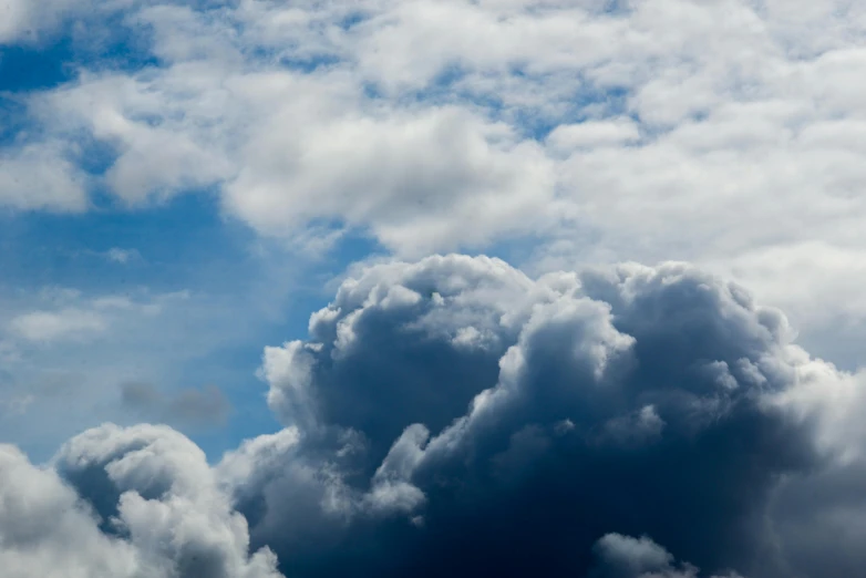 a plane flying through a cloudy blue sky, by Niko Henrichon, unsplash, dark mammatus cloud, big smoke clouds visible, image of the day, looking up onto the sky