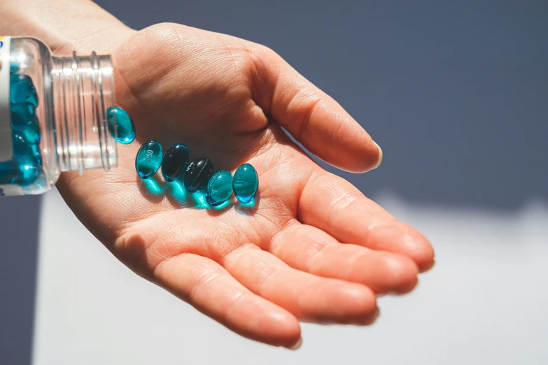 a close up of a person holding a bottle of pills, an illustration of, by Rachel Reckitt, unsplash, blue-green fish skin, gems, manuka, high quality product photo