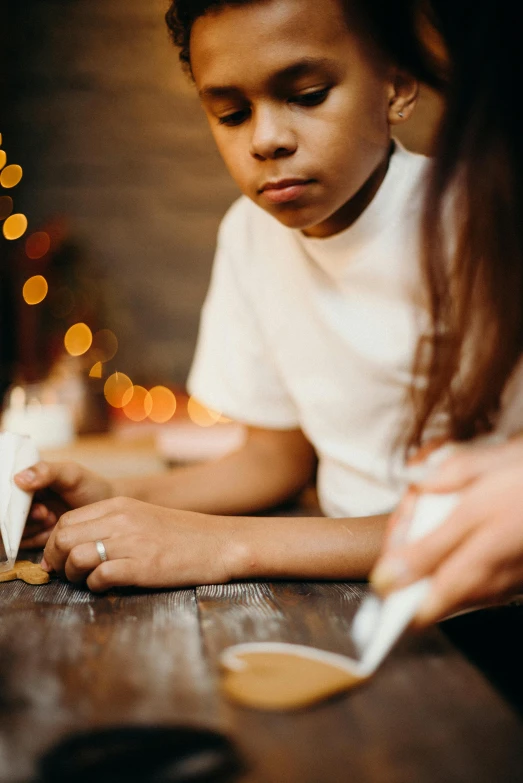 a little boy that is sitting at a table, pexels contest winner, visual art, white candles, paper origami, christmas night, caring fatherly wide forehead