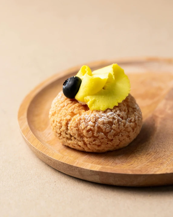 a pastry sitting on top of a wooden plate, inspired by Barthélemy Menn, unsplash, yellow, small nose, kousuke oono, no cropping