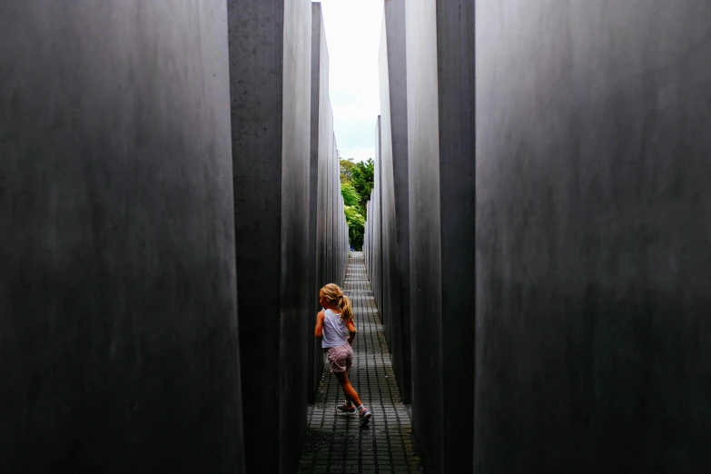 a little girl that is standing in the middle of a walkway, inspired by Thomas Struth, pexels contest winner, interactive art, untethered stelae, walter gropius, inside a tomb, statue of angela merkel