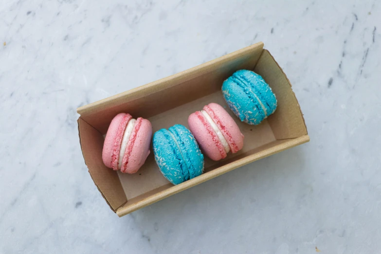 three macarons in a box on a table, blue and pink shift, front facing shot, mekka, teal silver red