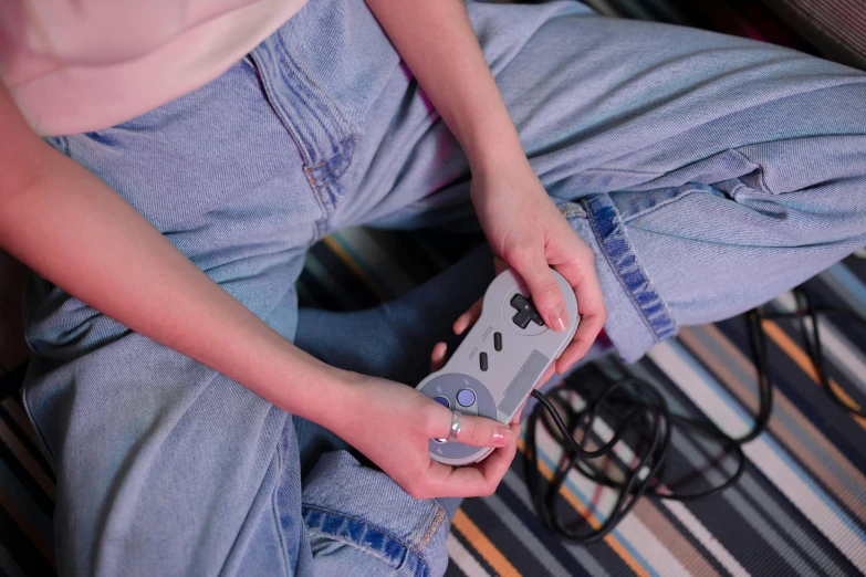 a close up of a person holding a nintendo wii controller, inspired by Elsa Bleda, trending on pexels, photorealism, 8 0 ies aesthetic, gray canvas, teenager hangout spot, full length shot