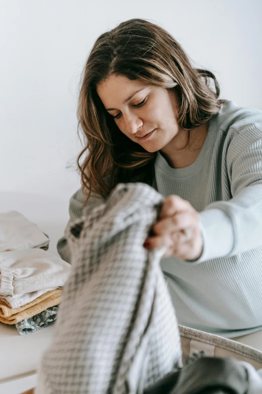 a woman is putting clothes in a basket, by Elizabeth Durack, trending on unsplash, cozy studio photography, double layer fold over hem, profile image, flannel