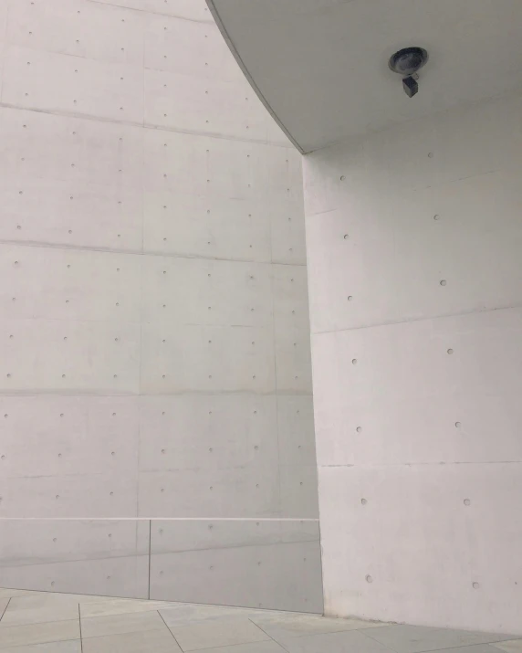 a man riding a skateboard up the side of a building, inspired by Leandro Erlich, reddit, light and space, made of all white ceramic tiles, interior of the hall in area 55, concrete _ wall ) ], low quality photo