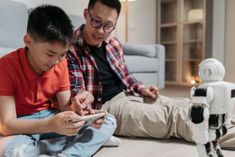 a man and a boy sitting on the floor looking at a cell phone, tabletop gaming, ren heng, fatherly, acnh