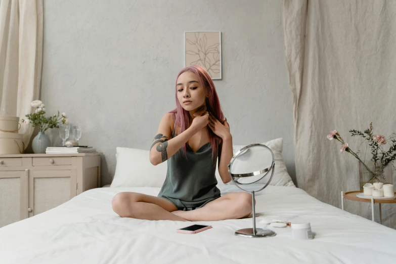 a woman sitting on a bed in front of a mirror, trending on pexels, wearing choker, asian female, with pink hair, relaxed posture