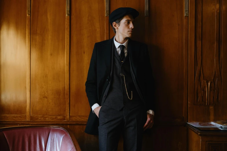 a man in a suit and tie leaning against a wall, an album cover, inspired by August Sander, pexels contest winner, renaissance, costumes from peaky blinders, tall hat, 1 9 2 0 s room, lachlan bailey