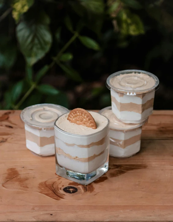 a couple of desserts sitting on top of a wooden table, inspired by Adam Dario Keel, sumatraism, 6 pack, floating spiral sand, product image, jars