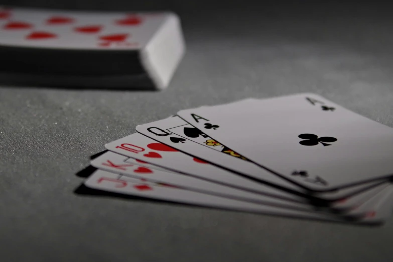 a pile of playing cards sitting on top of a table, pexels contest winner, photorealism, on a gray background, action shot, paul barson, solid grey