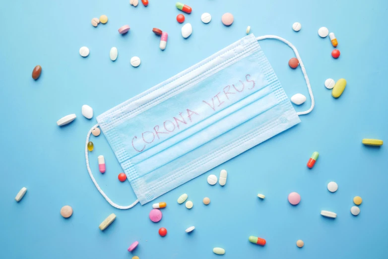 a medical mask with the word corona written on it surrounded by pills, shutterstock, visual art, wrapped blue background, candy pastel, around a neck, wide overhead shot