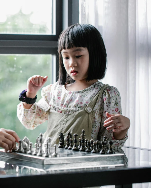 a boy and a girl playing a game of chess, inspired by Zhou Wenjing, pexels contest winner, interactive art, wearing silver dress, tiny girl looking on, as action figures, asian girl