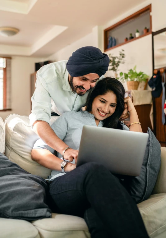 a man and woman sitting on a couch looking at a laptop, trending on reddit, indian, a still of a happy, uk, avatar image