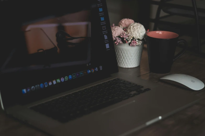 a laptop computer sitting on top of a wooden desk, pexels, sitting with flowers, night time footage, background image, table in front with a cup