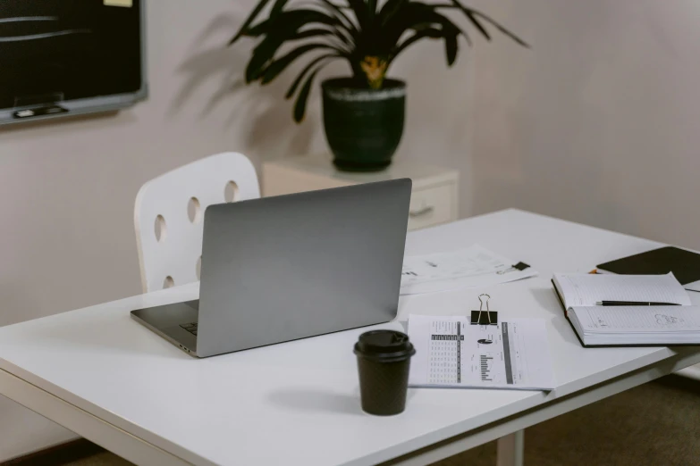 a laptop computer sitting on top of a white table, unsplash, ignant, office furniture, table in front with a cup, no type