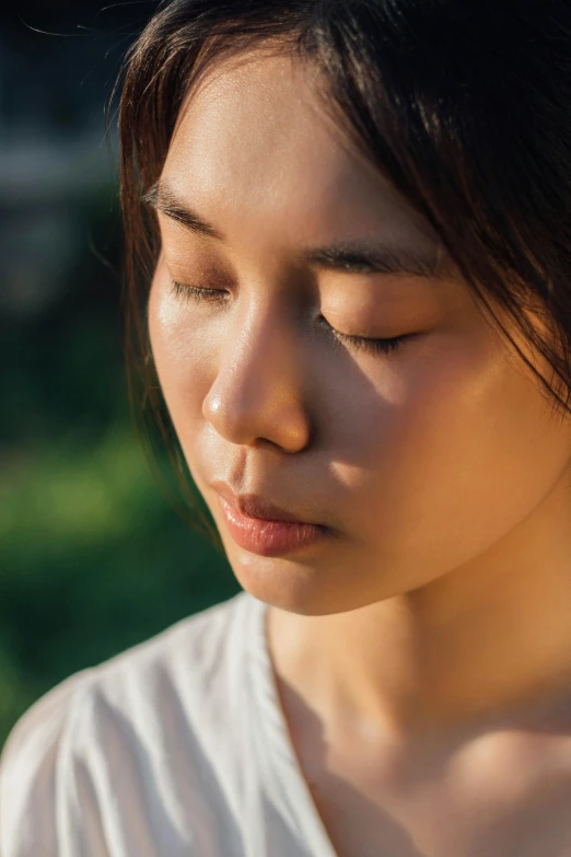 a close up of a person holding a cell phone, eyes closed, square facial structure, asian sun, meditation