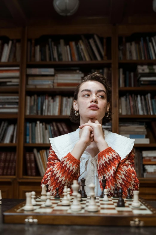 a woman sitting at a table in front of a chess board, inspired by Elsa Bleda, trending on unsplash, renaissance, standing inside a magic library, portrait of timothee chalamet, portrait of margot robbie, maisie williams