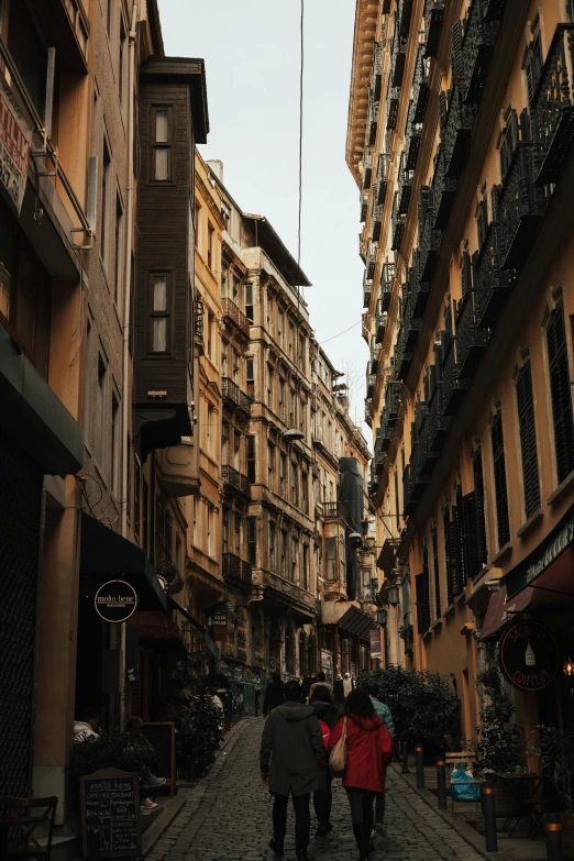 a couple of people walking down a cobblestone street, by Cafer Bater, pexels contest winner, neoclassicism, buildings covered with greebles, cairo, high rise buildings, warm light