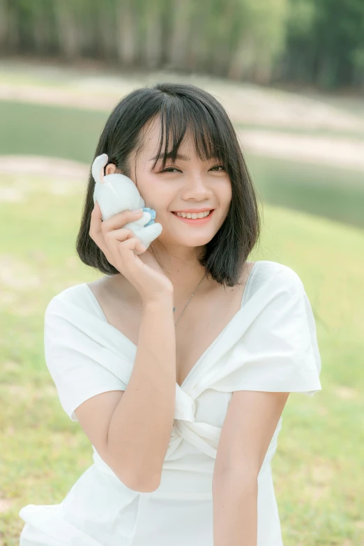 a woman in a white dress talking on a cell phone, by Ni Tian, wearing a cute top, patiphan sottiwilaiphong, skincare, holding controller