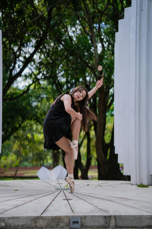 a woman in a black dress is doing a trick, by Basuki Abdullah, arabesque, summer day, full frame image, square, college