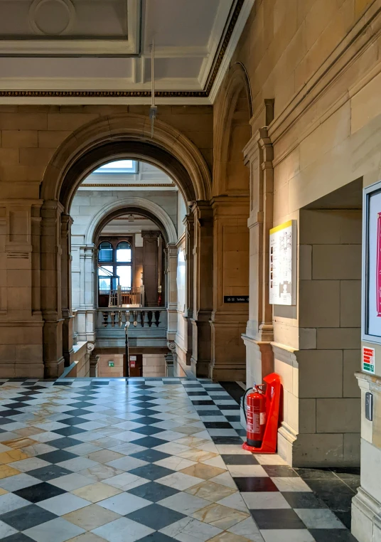 a hallway with a checkered floor and a red fire hydrant, poster art, inspired by Sydney Prior Hall, trending on unsplash, academic art, wide grand staircase, edinburgh, tall arched stone doorways, pritzker architecture prize