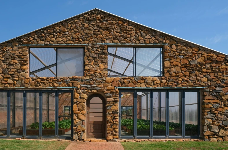 a stone house sitting on top of a lush green field, steel archways, glass studio, sandstone, exterior botanical garden