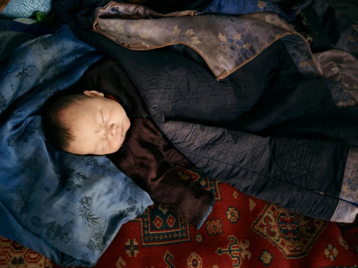 a baby wrapped in a blanket laying on a rug, by Alison Geissler, unsplash contest winner, hyperrealism, mongolia, annie lebowitz, dreaming bodies, portra