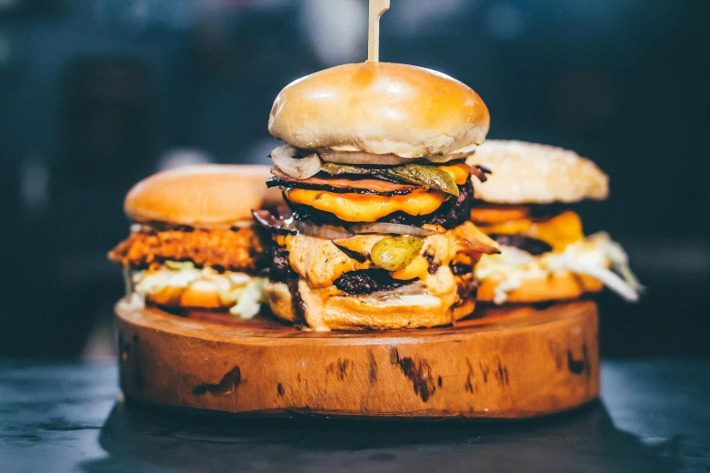 a stack of burgers sitting on top of a wooden cutting board, by Joe Bowler, unsplash, offering a plate of food, melbourne, 🦩🪐🐞👩🏻🦳, server in the middle