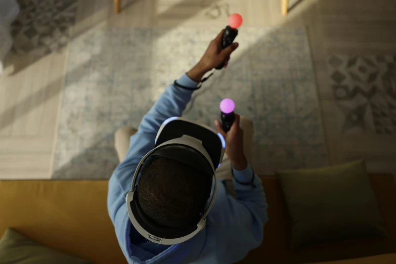 a man sitting on a couch holding a remote control, interactive art, oculus quest 2, head straight down, light from right, rear-shot