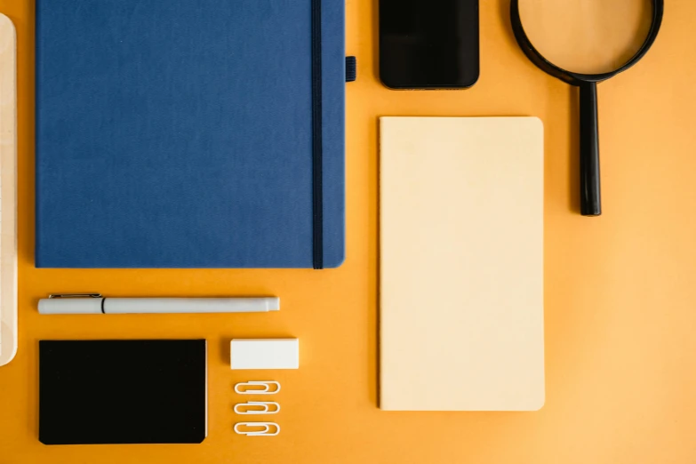 a laptop computer sitting on top of a desk next to a magnifying glass, trending on pexels, minimalism, yellow and blue color scheme, square shapes, various items, staples