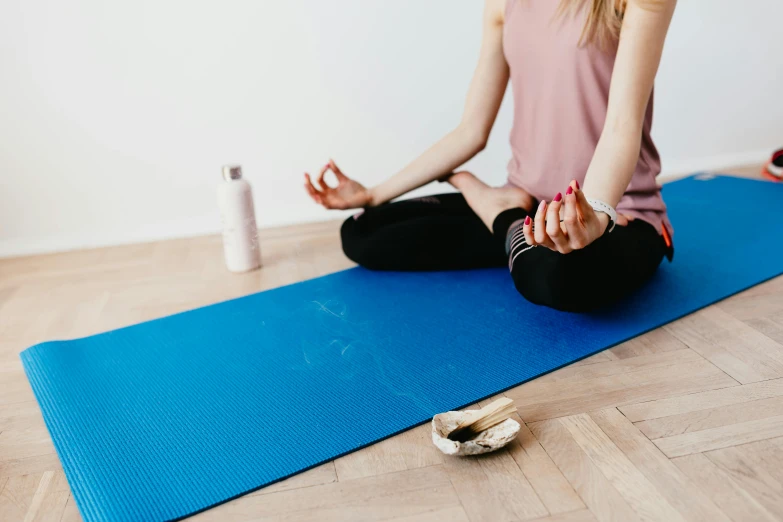 a woman sitting on top of a blue yoga mat, trending on pexels, background image, incense, studio floor, professional artwork