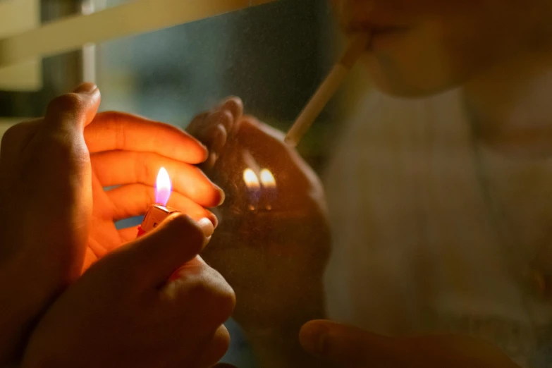 a close up of a person lighting a cigarette, a picture, light through glass, candle lighting, profile image