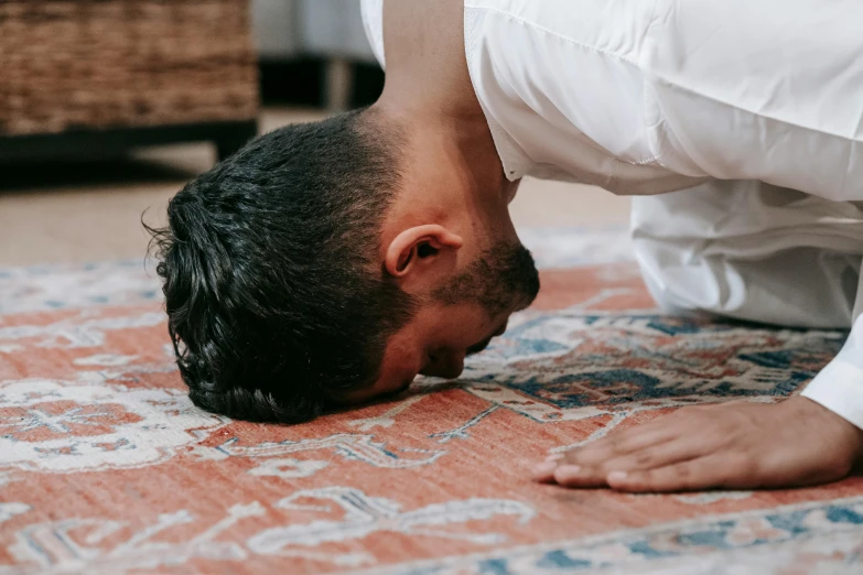 a man is doing a handstand on a rug, by Carey Morris, pexels contest winner, hurufiyya, kneeling in prayer, smelling good, lying on back, indoor setting