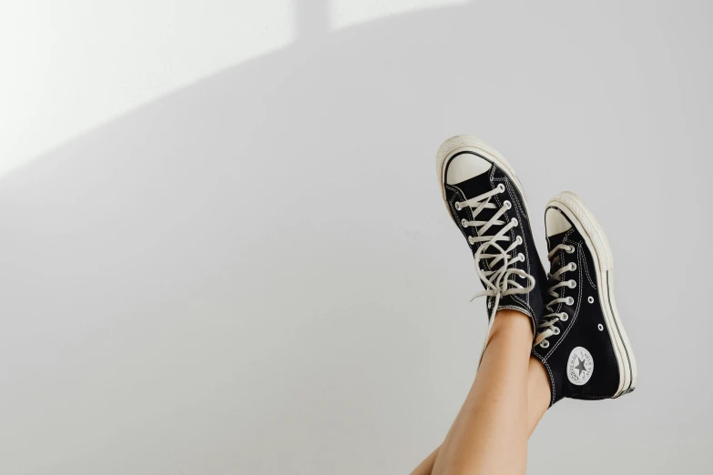 a close up of a person's legs wearing black converses, trending on pexels, sitting in an empty white room, summer feeling, background image, no watermarks