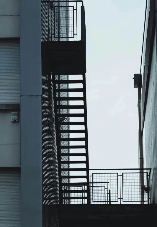 a man riding a skateboard down a flight of stairs, a photo, unsplash, postminimalism, fire escapes, tall factory, silhouette :7, tokyo alleyway