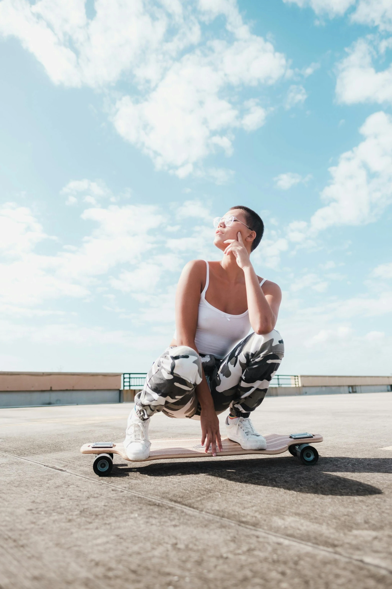 a woman sitting on a skateboard in a parking lot, in the sky, manly, profile image, happy vibes