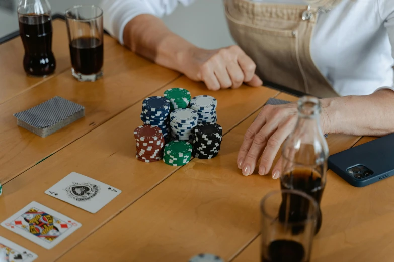 a woman sitting at a table playing a game of poker, by Daniel Lieske, pexels contest winner, cups and balls, on a wooden table, product introduction photo, thumbnail