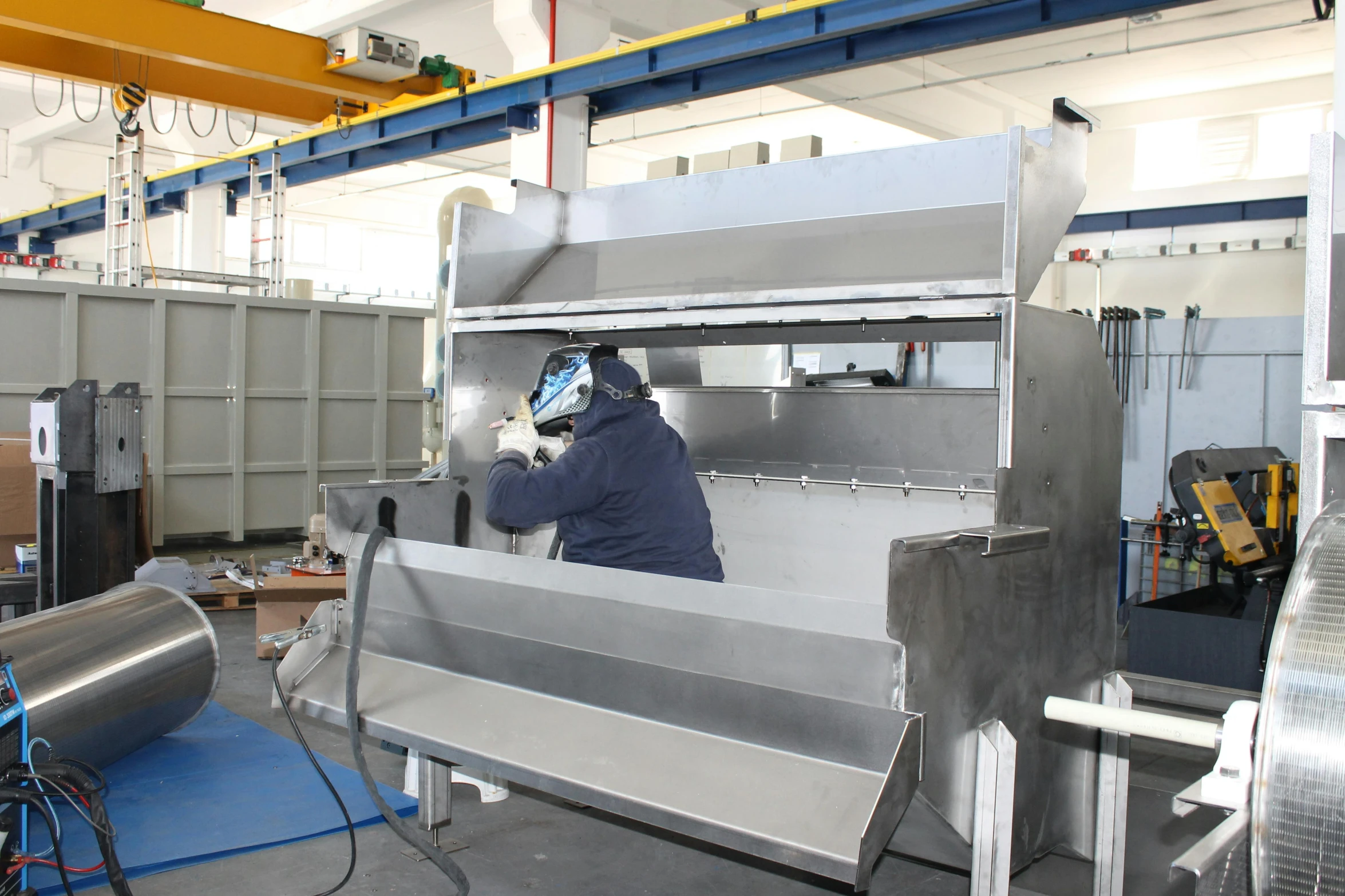 a man working on a machine in a factory, stainless steel, avatar image, hood, feed troughs